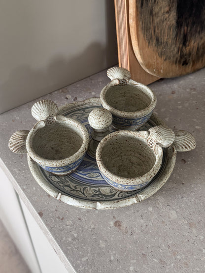 Set of ceramic pots with shell designs on a textured surface